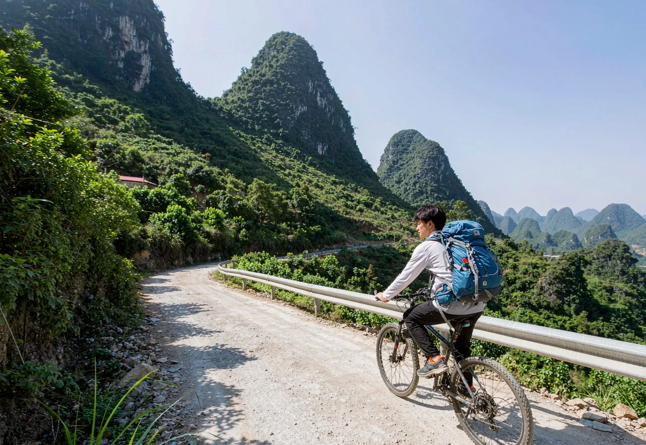 A backpacker cycling past karst peaks in Yangshuo, Guangxi