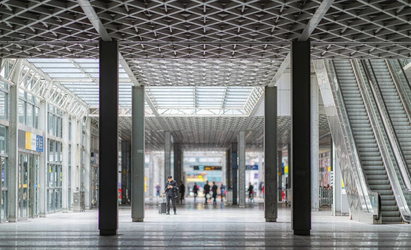 First-time visitor inside a modern Chinese high-speed train station concourse with escalators and English signage