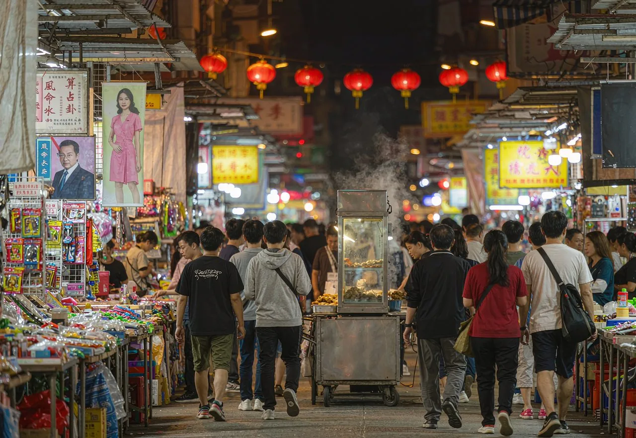 Temple Street Night Market at street level with crowded stalls, red lanterns and neon signs