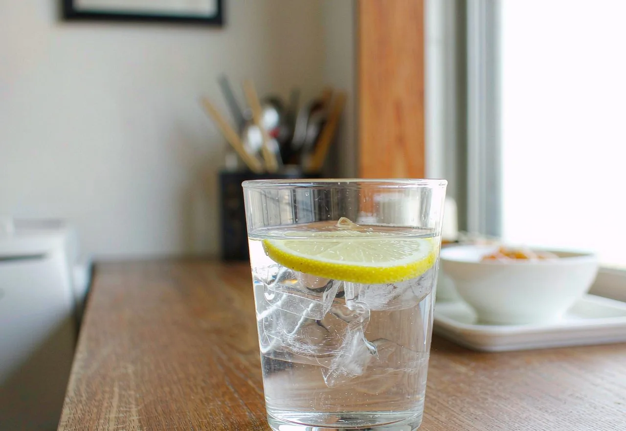 A glass of fresh drinking water on a table with a blurred Chinese city background - is tap water safe to drink in China?