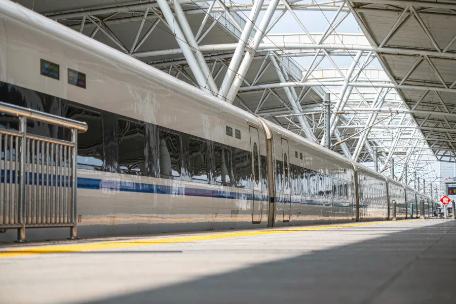 A busy high-speed rail station platform with departure boards above